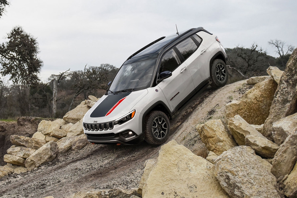 Vue latérale du Jeep Compass en pleine puissance sur une descente de roche escarpé